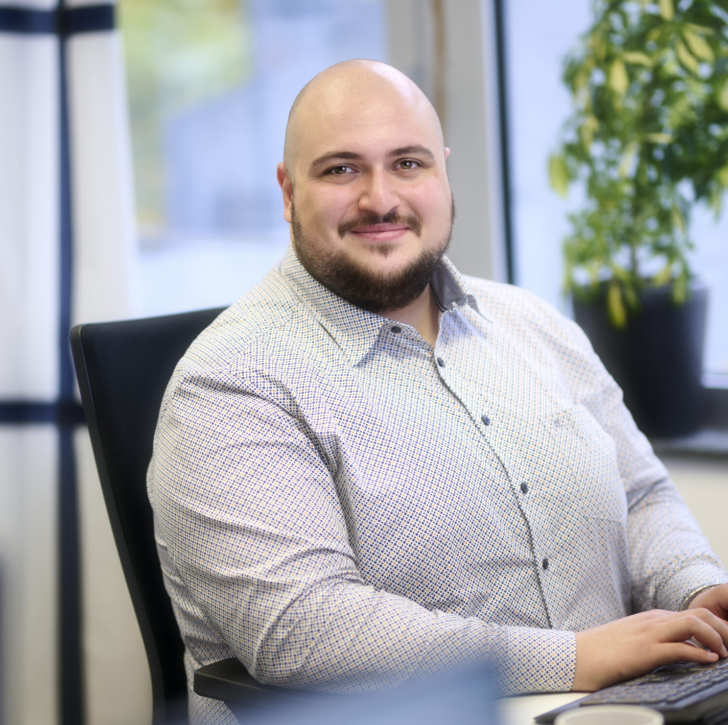 Mert Ambarcioglu, Projektleiter der Rietzler Energiekonzept in hellem Hemd, der an Laptop an Energieberatungen arbeitet